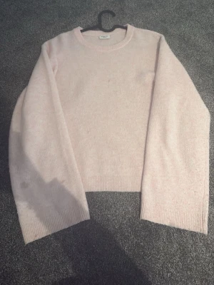 Ljusrosa stickad tröja Monki - Mysig ljusrosa stickad tröja från Monki med rund halsringning och långa ärmar. Tröjan har en enkel, rak passform och ribbade muddar vid ärmslut och nederkant. Perfekt för lager på lager och en soft vardagslook.