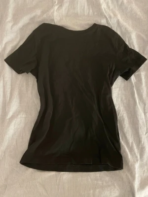 Svart basic t-shirt - En enkel svart t-shirt med rund hals och korta ärmar. Modellen är figurnära och passar perfekt till jeans eller kjol. Tillverkad i mjukt bomullstyg som känns skönt mot huden. Inga synliga tryck eller loggor för en clean look.❤️