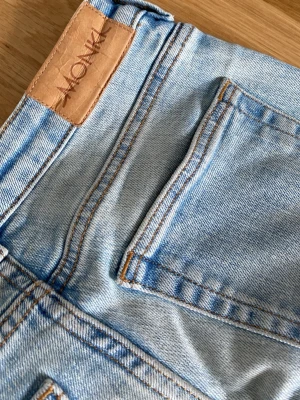 Ljusblå utsvängda jeans från Monki - Säljer ett par ljusblå jeans från Monki med utsvängda ben och är lågmidjade. Skicket är helt nytt, inte söndriga alls. De ser lite skrynkliga ut för de har legat i min låda väldigt länge. Storlek 24/32 priset kan diskuteras 