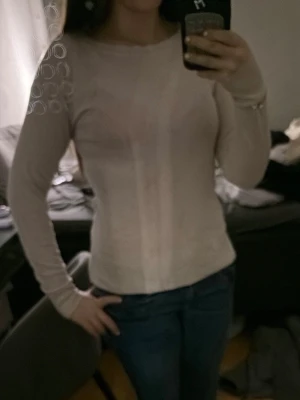 Beige långärmad topp med slits - Säljer en beige långärmad topp med diskret slits på sidan. Toppen har en enkel och clean design med rund hals och är gjord i ett mjukt material som känns skönt mot huden. Från hm.