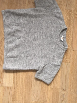 Grå stickad t-shirt i ullmix - Säljer en kortärmad tjocktröja från Gina tricot. Den en ett litet hål vid framsidan och priset kan diskuteras