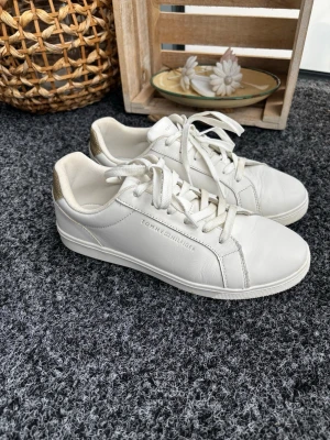 Tommy Hilfiger vita lädersneakers - Mycket sparsamt använda pga aningen för små för mig (är mittemellan strl 40-41). Lite smuts på skosnörena, se bild. Jättefina i övrigt, inga fläckar på lädret. 