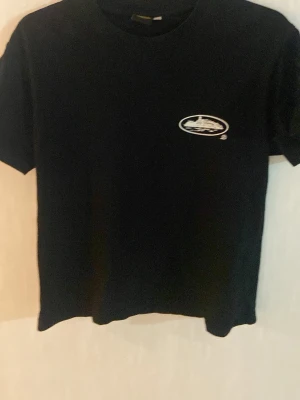 Svart Cortez t-shirt med logo  - Svart t-shirt med rund hals och korta ärmar. På bröstet och ryggen finns ett vitt tryck med motiv av ett fartyg inuti en oval. T-shirten har en klassisk passform och är gjord i mjukt bomullsmaterial.