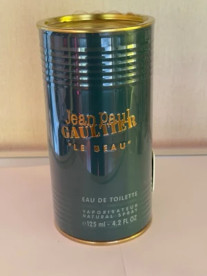 Jean Paul Gaultier Le Beau EdT 125ml - Jean Paul Gaultier Le Beau Eau de Toilette i en snygg grön metallburk med gulddetaljer. Flaskan rymmer 125 ml och har en unik, stilren design som sticker ut på hyllan. Perfekt för dig som gillar exklusiva och trendiga dofter.