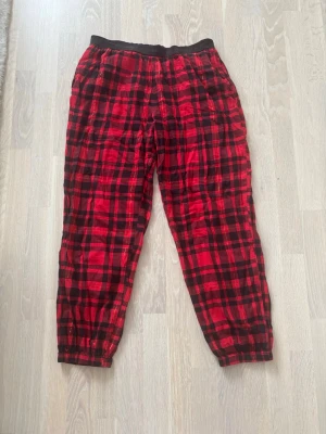 Rödrutiga pyjamasbyxor Victoria's Secret - Säljer ett par rödrutiga pyjamasbyxor från Victoria's Secret. Byxorna har svart resår i midjan med logga, klassiskt rutmönster i rött och svart samt avslappnad passform. Perfekta för mysiga hemmakvällar. Nya utan prislapp, bara legat i min låda! 