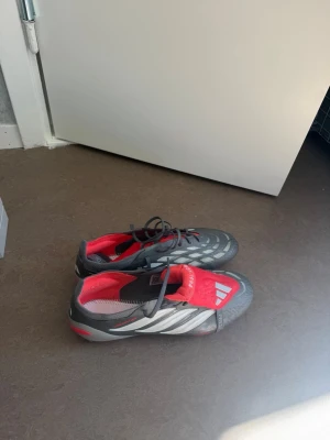Grå och röda Adidas fotbollsskor - Säljer ett par gråa och röda Adidas fotbollsskor. Dem är i ett helt nytt skick i storlek 41.