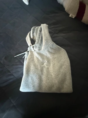 Grå hoodie med broderad logga - Säljer en stilren grå hoodie med huva med en liten logga framtil. Perfekt för en chill outfit!