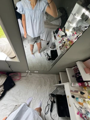 Ljusblå blus med puffärm - Söt ljusblå blus med puffiga korta ärmar och v-ringad hals. Blusen har en avslappnad passform och tunna, luftiga material som passar perfekt till sommaren. Enkel men trendig design som är lätt att matcha med olika stilar.