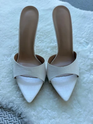 Eleganta vita klackskor - Ett par vita pumps med öppen häl och spetsig tå i konstläder design med en elegant finish. Dessa pumps är nästan helt nya, säljes pga att de är för höga för mig.