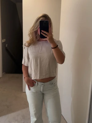 Ljusbeige croppad blus - Säljer denna superfina silkes T-shirt från MQ. Den ser tyvärr lite tråkig ut på bilden för att den inte är strykt. Den är väldigt luftig och glänser när den är strykt och fin 🥰🥰