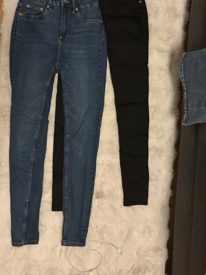 Två par skinny jeans blå & svarta - Säljer två par skinny jeans, ett par i klassiskt blå denim och ett par i svart. Båda har fem fickor och normalhög midja. Perfekta till alla dina outfits och sitter riktigt snyggt med sin tighta passform.
