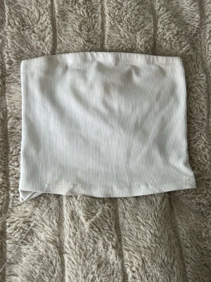 Vit ribbad bandeau tubtopp H&M Divided - Säljer en vit ribbad bandeau tubtopp från H&M Divided. Fåtal trådar som sticker ut men dom kan man ba klippa av