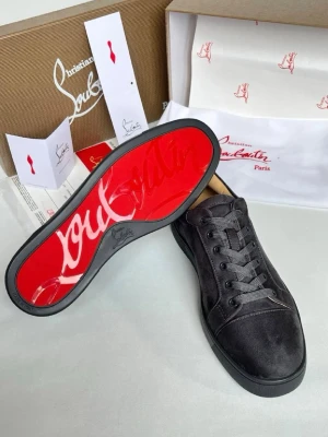 Svarta sneakers från Christian Louboutin - Snygga svarta sneakers från Christian Louboutin med klassisk röd sula och diskret logga. Skorna har en låg siluett, ovandel i mocka och textil, samt svarta skosnören. Perfekta för dig som vill ha en clean och exklusiv look.