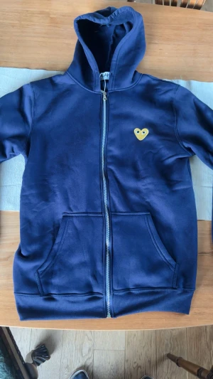 Commes Des Garcons Play zip up - Mörkblå CDG zip up storlek S, ny med lappar endast testad. Drog ut snörerna när jag testade den då jag inte gillade dom men dom följer såklart med och är bara att sätta in igen. Hör av er med eventuella frågor.