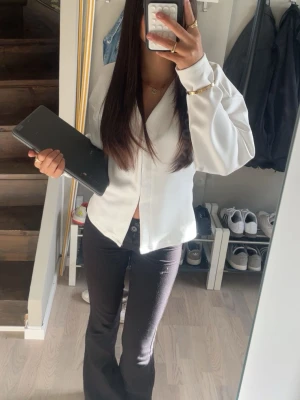 Vit skjorta med knappar - Säljer en stilren vit skjorta med knappar framtill. Skjortan har en klassisk krage och långärmade ärmar med lätt loose passform. Perfekt för dig som vill ha en enkel och snygg look.