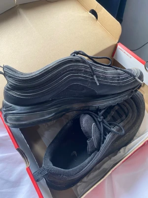 Nike air Max 97 svarta (kvitto finns köpta för 2300) - Säljer ett par Nike Air Max 97 “Triple Black” i storlek 46. Klassisk modell med hel Air-sula som ger bra komfort och stilren look. Skorna är använda men i bra skick perfekta till vardagen. Pris kan dissekeras vid snabbare affär. Kvitto finns kvar