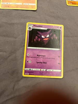 Pokémonkort Haunter lila - Säljer ett Pokémonkort med Haunter. Kortet är lila med gul kant och har Haunter-illustration i mitten. Text och attacker står på engelska. Perfekt för samlare eller Pokémon-fans.