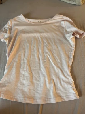 Ljus ljus rosa t shirt - Enkel och stilren rosa t-shirt i mjuk bomull. Modellen är klassisk med rund halsringning och korta ärmar. Perfekt att matcha med jeans eller shorts för en avslappnad look.