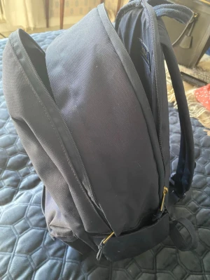 Mörkblå ryggsäck från Polo Ralph Lauren - Snygg mörkblå ryggsäck från Polo Ralph Lauren med klassisk röd broderad logga framtill. Tillverkad i slitstark canvas med justerbara axelband och dragkedja. Perfekt för skola eller cityhäng.