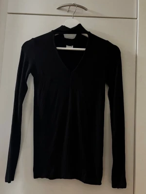 Svart tröja från Gina Tricot - Storlek XS - Svart långärmad tröja med trendig choker och V-ringning! Perfekt både till vardag och fest – lätt att matcha med allt från jeans till kjol! Varumärke: Gina Tricot. Storlek: XS. Material: 95% Viskos och 5% Elastan. Kika gärna in på mina andra annonser, jag säljer flera plagg just nu! Hör av dig vid frågor eller intresse!