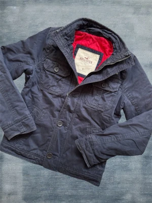 Marinblå Hollister Fieldjacket - En mycket trevlig fieldjacket type jacka från märket Hollister! Hör av dig vid frågor! 