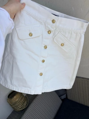 GANT kort vit sommarkjol strl 34 nyskick - Snygg vit kortkjol från GANT  med raka linjer och dekorativa guldknappar framtill. Perfekt för dig som gillar en stilren och trendig look.🌸