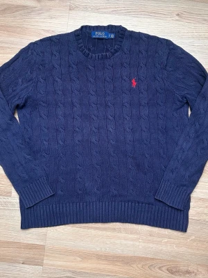Marinblå Polo Ralph Lauren Kabelstickad Tröja - Storlek S, insydd i nacken för bättre passform runt halsen, syns ej vid användning.