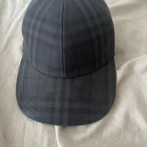 Burberry keps  - Säljer denna snygga och stilrena Burberry-keps i mörkgrått med det klassiska rutmönstret. Storlek: S Köpt i augusti förra året, kvitto finns som bevis på äkthet.  Kepsen är i mycket fint skick – knappt använd och känns som ny.  Finns för upphämtning i Göteborg, kan även frakta. 