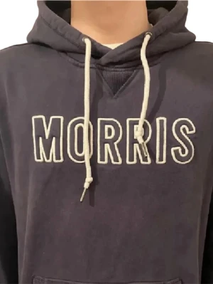 Mörkblå hoodie från Morris - Snygg mörkblå hoodie från Morris med vit broderad logga på bröstet och vita dragsnören i huvan. Klassisk känguruficka framtill och mjukt material som känns skönt mot huden. Perfekt för en avslappnad och trendig stil. (Pris kan diskuteras)🤩