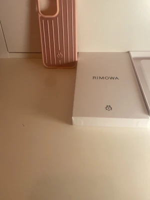  Rimowa mobilskal iPhone 17 - Snyggt rosa mobilskal från Rimowa med vertikala ränder och stilren design. Skalets material känns tåligt och har en matt finish. Perfekt för dig som vill ha ett trendigt och skyddande skal till din mobil. Levereras i originalförpackning.