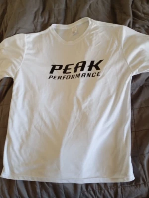 Ny t-shirt - Ny vit t-shirt  med svart logga tryckt på bröstet. Klassisk rund halsringning och korta ärmar. Perfekt för en clean och sportig stil.