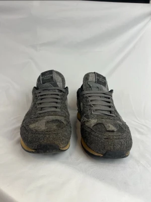 Grå Rockrunners skor från Valentino STR 41 - Unika sneakers från Valentino i olika nyanser av grått med kamouflagemönster. Ovandelen är i filtliknande material och skorna har grå skosnören samt beige sula med svart yttersula. Perfekta för dig som vill sticka ut med stilrena detaljer.Storlek: 41 Färg: Grå Skick: Väldigt fint skick. Skriv för mer info och bilder, pris kan diskuteras