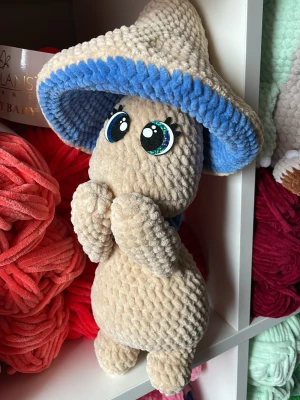 Mushroom guy beige/blå - Supergullig Mushroom guy formad som en svamp då så klart med stora glittriga filtögon i blått. Tillverkad i beiget sammetsgarn med blå kant inuti hatten. Perfekt som dekoration eller kramkompis för dig som gillar söta figurer.