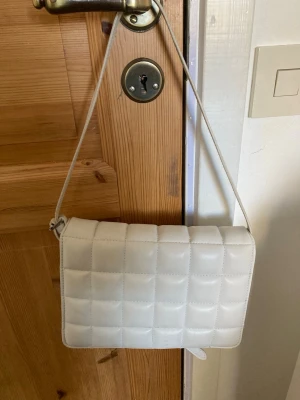 Vit handväska!! - Vit lite puffig handväska med reglerbart handtag. Rymmer relativt mycket!