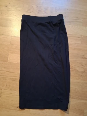 Svart långkjol i bomull - En enkel svart långkjol i mjukt bomullsmaterial. Kjolen har rak passform och resår i midjan för bekväm passning. Perfekt att styla med både sneakers och boots.