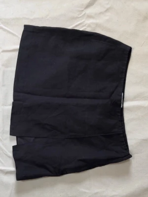 Svart kortkjol från H&M i bomull - Svart kortkjol från H&M i storlek 38. Kjolen är enkel och stilren med rak passform och slits framtill. 