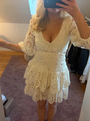 Vit spetsklänning med volanger - Superfin vit/beige kortklänning i spets med v-ringning och volangdetaljer. Klänningen har trekvartsärm. Köpte här på Plick men har själv aldrig använt den. Märket är golden days. Bilderna är från förra ägaren, men kan skicka fler egna bilder om så önskas💕