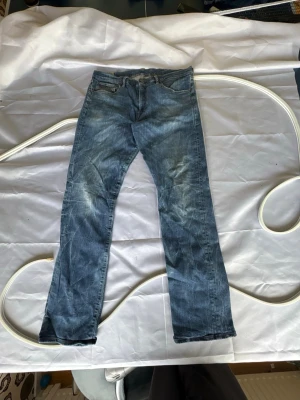 Blå Ralph Lauren jeans med fades - Säljer ett par blå jeans med rak passform och klassisk femficksdesign. Jeansen har en snygg tvättad look med ljusa slitningar på låren och knäna. Tillverkade i denim som ger en avslappnad och tidlös stil. Perfekta för dig som gillar en enkel och clean look. W36 L34