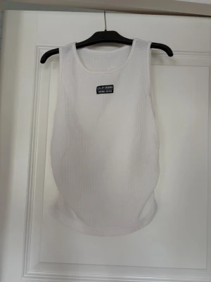 Vit ribbad linnetopp  - Vit ribbad linnetopp med trycket ’California Original Design’. Toppen är ärmlös med rund halsringning och har ihopsydda sidosömmar.