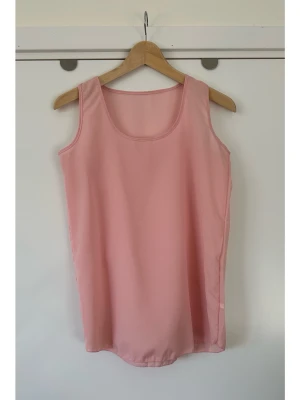 Ljusrosa ärmlöst linne, storlek M - En stilren ljusrosa topp / linne med rund halsringning och ärmlös design. Toppen är tillverkad i ett lätt och luftigt material, perfekt för varma dagar. Det står storlek L, men är en M. Enkel och snygg att matcha med olika outfits. Mycket gott skick, som ny!