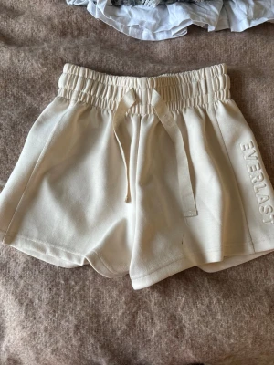 Beiga shorts från Everlast med snörning - Snygga beiga shorts från Everlast med elastisk midja och snörning framtill. Mjukt material och broderad logga på ena benet. Perfekta för en avslappnad stil eller träning.