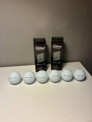 Titleist Pro V1 golfbollar 6-pack - Säljer ett 6-pack vita golfbollar av modellen Pro V1 från Titleist. Bollarna levereras i två svarta förpackningar med fönster, där varje boll har klassisk dimple-design och tydlig märkning. Perfekt för dig som vill ha premiumkänsla på golfbanan.