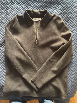 Brun tröja med dragkedja från Samsoe Samsoe - Snygg brun långärmad tröja från Samsoe Samsoe med krage och halv dragkedja framtill. Tröjan har en stilren design och är tillverkad i ett mjukt material som känns skönt mot huden. Perfekt för en avslappnad men ändå uppklädd look.