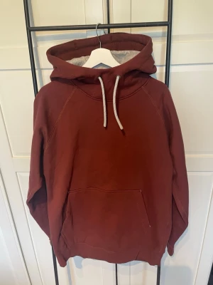 Vinröd hoodie med magficka Pelle P - Snygg vinröd hoodie från Pelle P med stor huva, vita dragsnören och en praktisk magficka. Mjuk insida och diskret logga broderad på huvan. Perfekt för en avslappnad och trendig stil. Storlek S men passar även M.  Tröjan är helt oanvänd med prislappen på. Nypris ligger på ca 1500kr