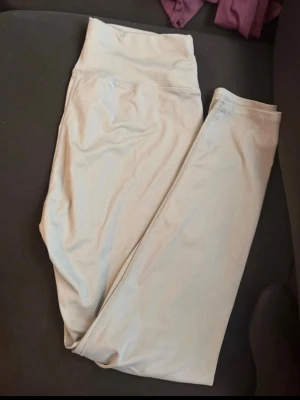 Ljusgrå leggings i polyester XL - Snygga ljusgrå leggings i storlek XL, tillverkade i stretchigt material med 92% polyester och 8% elastan. Perfekta för dig som vill ha bekväma och stilrena leggings till vardags eller träning. Hög midja och enkel design utan mönster.