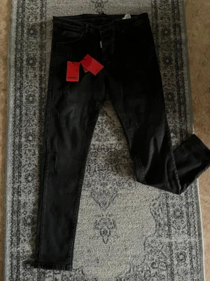 Svarta skinny jeans från Dsquared2 - Säljer ett par svarta skinny jeans från Dsquared2 med slitna detaljer och klassisk femficksdesign. Jeansen har en modern passform och är tillverkade i stretchigt denim för extra komfort. Perfekta för dig som gillar en edgy stil.