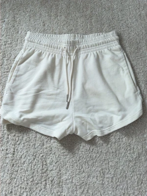Vita shorts med snörning - Snygga vita shorts med elastisk midja och snörning framtill. Tillverkade i mjuk bomull för maximal komfort. Perfekta för varma dagar och har en enkel, clean look med fickor på sidorna.