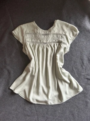 Ljusgrön blus med spetsdetaljer - THE CUTEST everyday blouse for spring/summer. Soft flowy fit with beautiful vintage-inspired details in a light sage/natural green color. Very feminine & romantic. Would style it with low rise jeans or a mini skirt🌷  NO FLAWS except the button loop has come loose, but it can be easily fixed with a needle and thread. Otherwise perfect condition🤍 