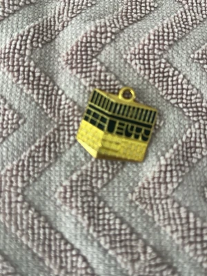 Två guldiga berlocker med Kaba-motiv - Två berlocker i metall med motiv av Kaba i Mekka. Den ena är fyrkantig med svart och guldfärg, den andra är rund med detaljer i grönt och guld. Perfekta som hängen till halsband eller armband för dig som vill ha en unik och personlig accessoar.