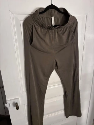 Khaki mjukisbyxor från KAY/DAY - Snygga khaki mjukisbyxor från KAY/DAY med bred resår i midjan och raka ben. Tillverkade i ett mjukt och bekvämt tyg som passar perfekt för en avslappnad stil. Enkla att matcha med hoodies eller t-shirts för en chill look.